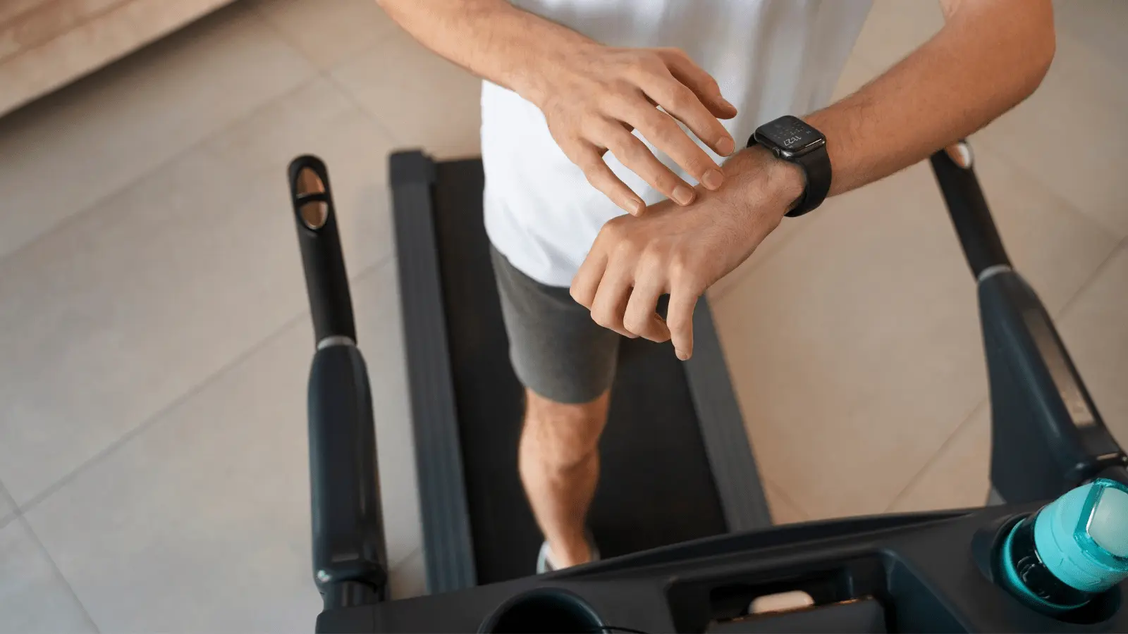 Primo piano di un uomo che controlla il suo cardiofrequenzimetro su uno smartwatch mentre corre su un tapis roulant. Monitoraggio della frequenza cardiaca durante l'allenamento.